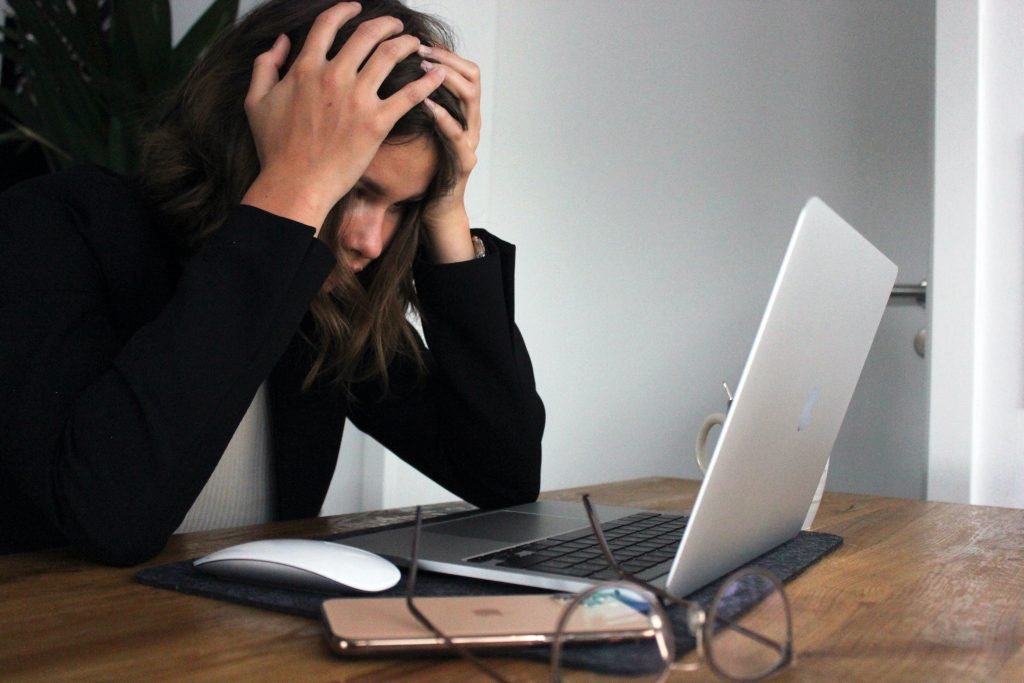 Woman staring at computer, holding her head in despair